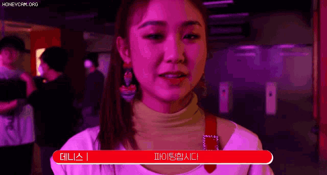 a woman in a pink shirt is standing in front of a red sign that says ' i 'm sorry ' .