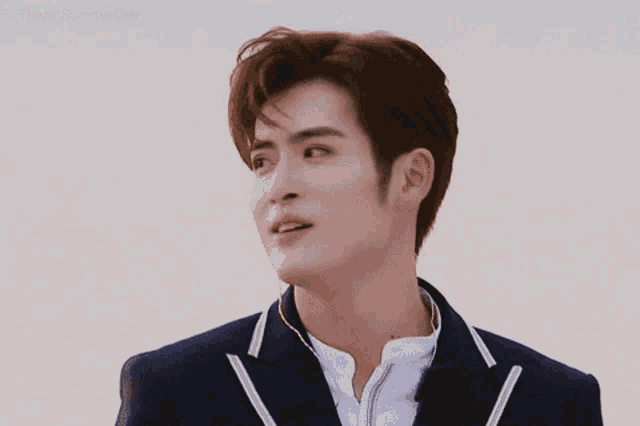 a young man wearing a suit and a white shirt looks at the camera .