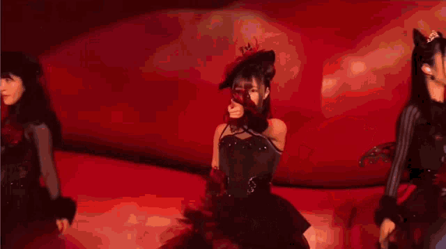 a woman with a microphone on her head is dancing on a stage in front of a red background .
