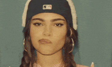 a close up of a woman wearing a hat and earrings .