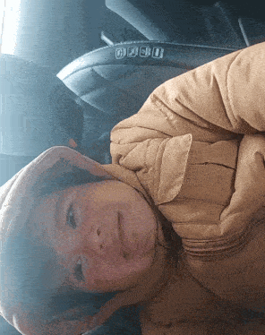 a person wearing a jacket with a hood is laying in a car seat that says casio