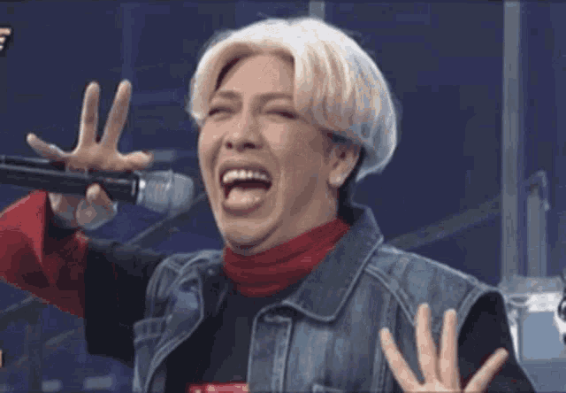 a man in a wig is holding a microphone and laughing .