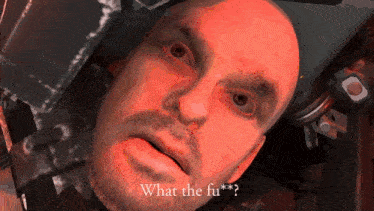 a man with a beard is laying in a red light and says what the fu * ?