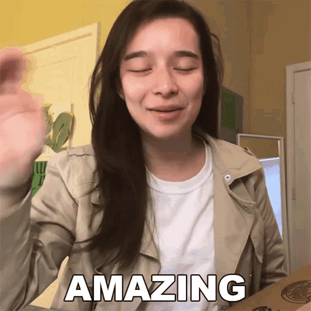 a woman in a tan jacket says " amazing " in front of a pizza box