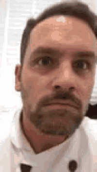 a man with a beard is making a funny face in a close up of his face .