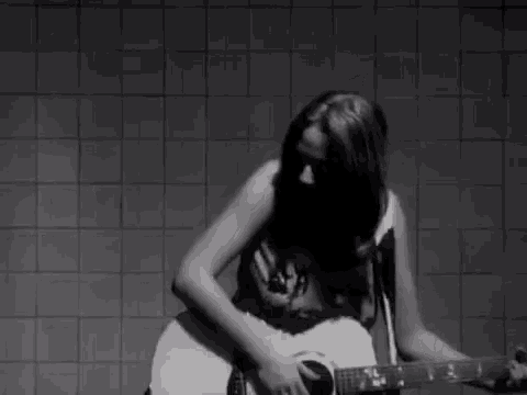 a woman is playing an acoustic guitar in a bathroom