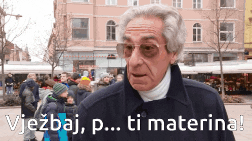 a man in a black coat stands in front of a crowd with the words vjezdaj p..ti materna