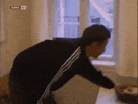 a man in a black and white adidas tracksuit looks out a window