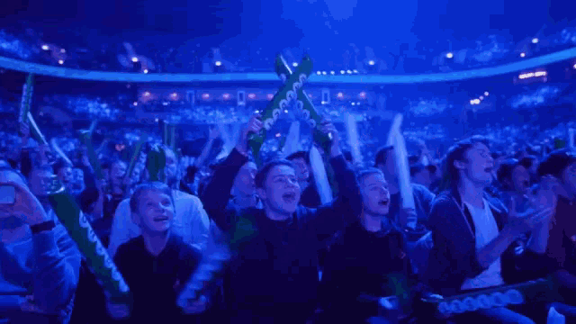 a crowd of people in a stadium holding up green foam sticks with the word xbox on them