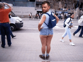 a man wearing shorts and a backpack is standing in front of a wall that says ' china is a nation '