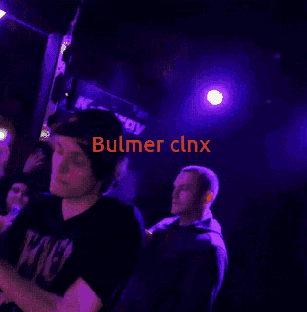 a man stands in front of a crowd with the name bulmer clnx on the bottom right