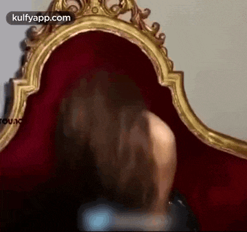a woman is looking at herself in a mirror while sitting on a red couch .