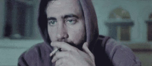 a man with a beard wearing a hoodie is sitting at a table .