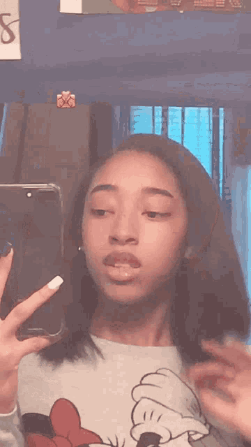a girl is taking a selfie in front of a mirror wearing a minnie mouse shirt