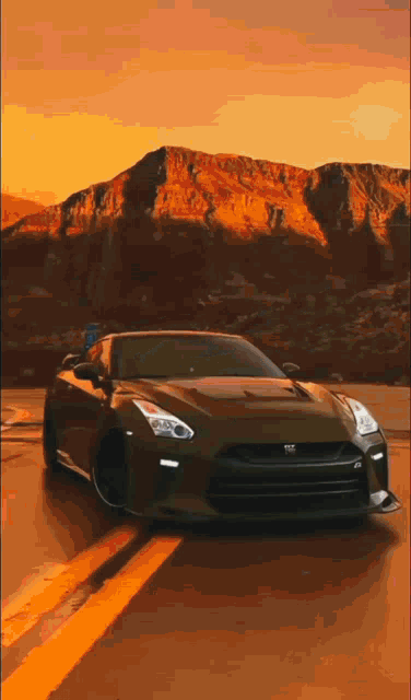 a car is driving down a road in front of mountains