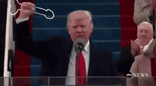 a man in a suit and tie is standing in front of a microphone with a penis drawn on it .