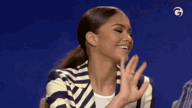 a woman wearing a striped jacket is clapping her hands .