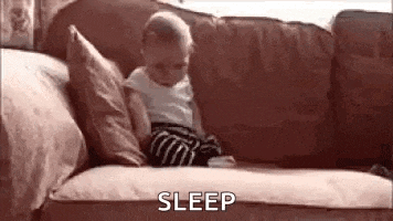 a baby is sitting on a couch with pillows and a blanket .