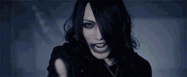 a woman with long black hair is wearing a black shirt and a necklace