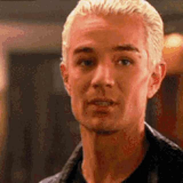 a close up of a man with blonde hair and a black shirt .