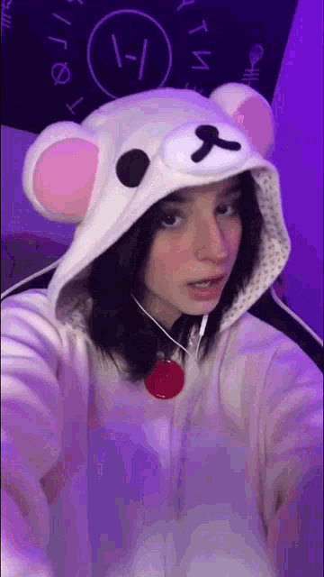 a girl is wearing a teddy bear hoodie and taking a selfie with headphones .