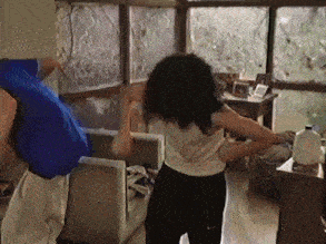 a man and a woman are dancing in a living room in front of a window
