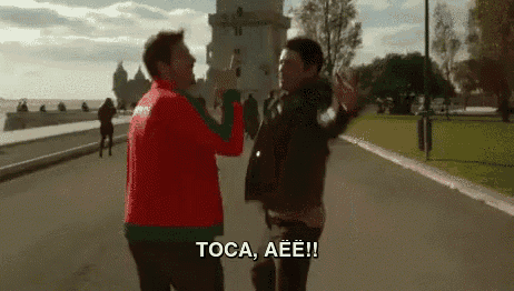 two men are giving each other a high five while standing next to each other on a street .