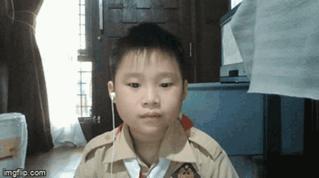 a young boy wearing ear buds looks at the camera with imgflip.com at the bottom of the screen
