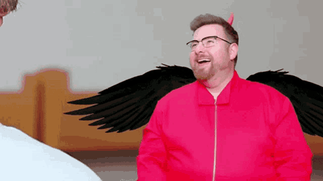 a man in a red jacket with black wings and horns is laughing