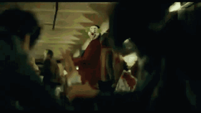 the joker is wearing a clown mask and standing in a crowd of people .