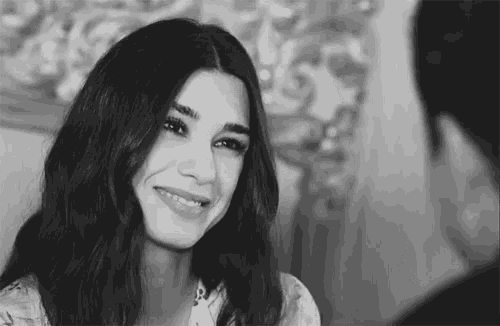 a black and white photo of a woman smiling and looking at a man .