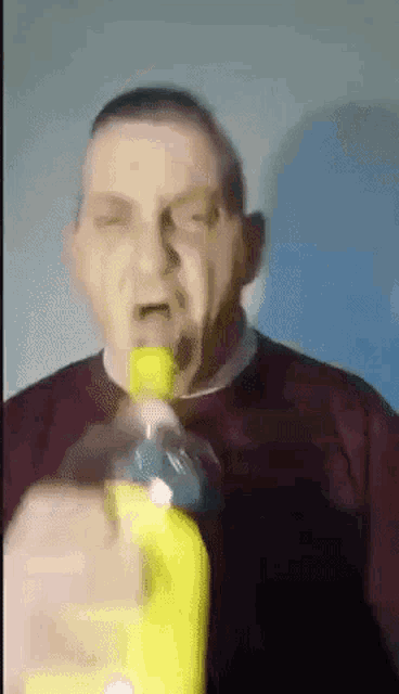 a man is holding a yellow bottle in his mouth