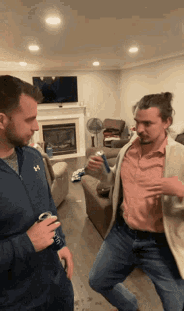 a man wearing a blue under armour jacket holds a can of bud light