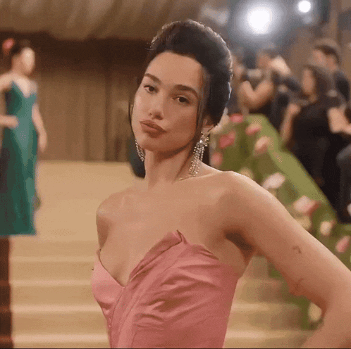 a woman in a pink strapless dress is standing on a set of stairs .