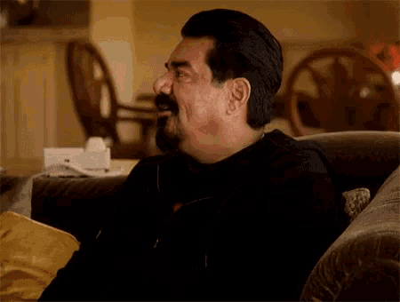 a man with a beard is sitting on a couch with his mouth open
