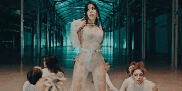 a woman in a white outfit is standing in a hallway surrounded by people