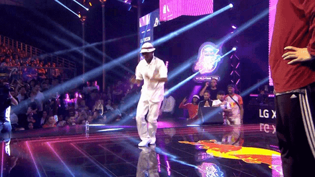 a man in a white hat is dancing on a stage in front of an lg sign