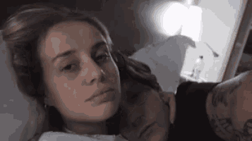 a woman with a tattoo on her arm is laying next to a man in bed