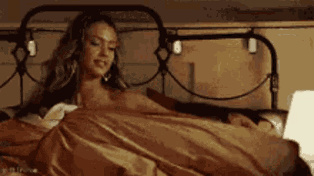 a woman is laying in bed with a man and a laptop .