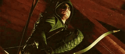a man in a green costume is holding a bow and arrow in his hand .