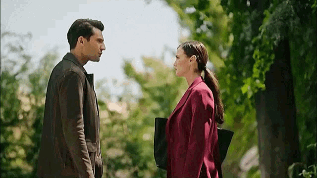 a man and a woman standing next to each other in a park
