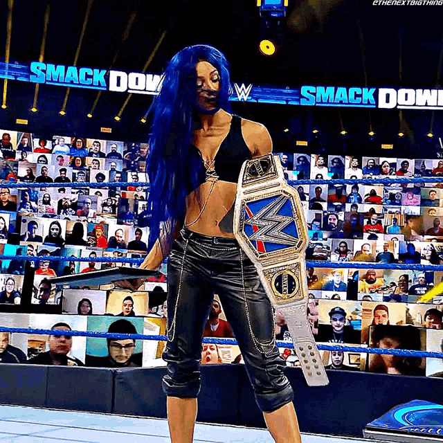 a woman in a wrestling ring holding a smack down championship belt