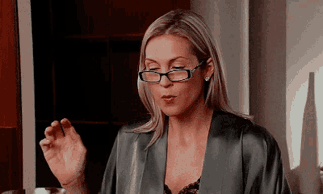a woman wearing glasses and a robe is making a gesture