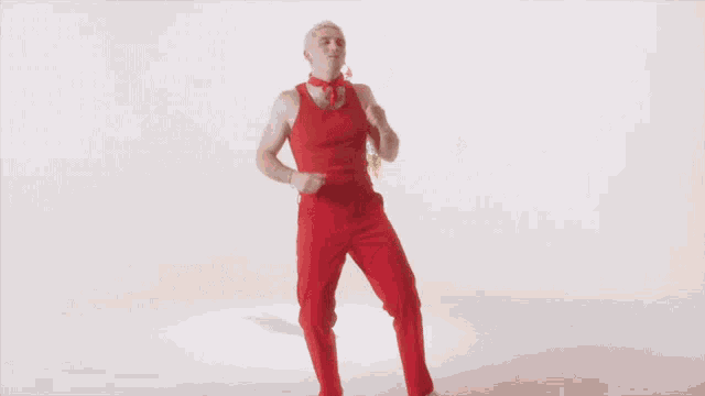 a man in red pants and a red tank top is holding a colorful toy