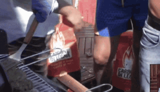 a man is cooking food on a grill with a bag of carbone di legna .