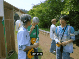 a group of young men are standing on a path and one of them is wearing a shirt that says ' seoul '