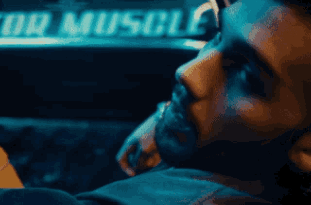 a close up of a man 's face in front of a sign that says muscle