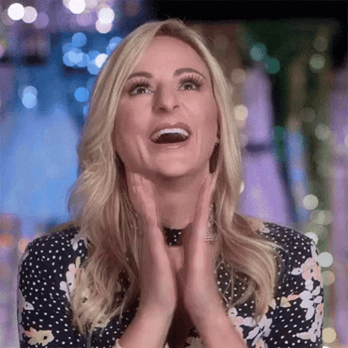 a woman in a polka dot dress is laughing and clapping her hands .