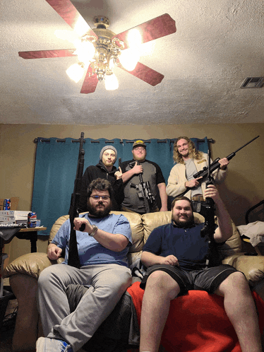 a group of men sitting on a couch with guns in their hands
