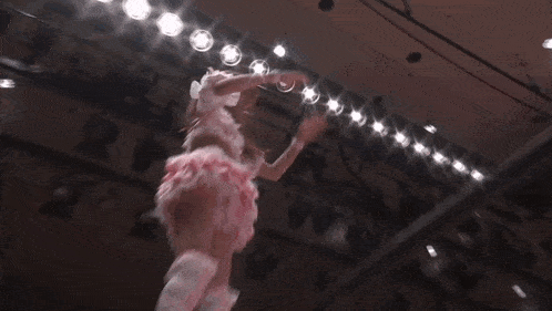 a woman in a pink dress is jumping in the air while a referee looks on